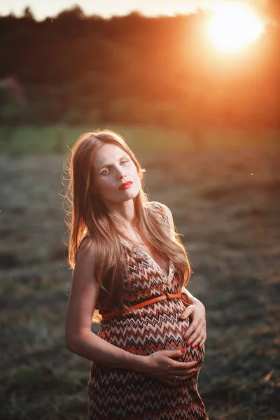 Junge schwangere Frau im Park im Freien. ruhige Schwangere im dritten Trimester. Wandern im öffentlichen Garten. Sonnenuntergang im Wald — Stockfoto