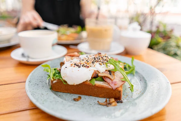 여름 카페에서 아침 식사와 커피. 베이컨, 버섯, arugula 및 데친 달걀을 가진 롤빵에 샌드위치 — 스톡 사진