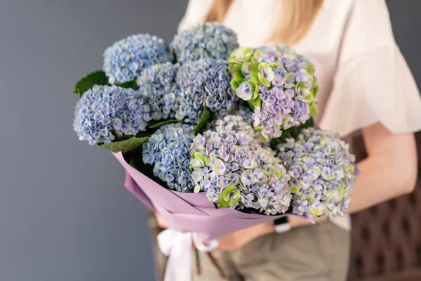 Small Beautiful bouquet of hydrangea flowers in woman hand. Floral shop concept . Beautiful fresh cut bouquet. Flowers delivery