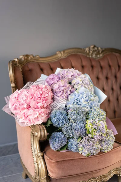Bouquets of hydrangeas lying on vintage sofa. Small Beautiful bouquet of hydrangea flowers. Floral shop concept . Beautiful fresh cut bouquet. Flowers delivery