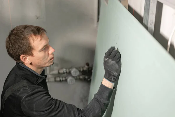 빌더를 작업하는 남자는 전기 배선 건식 벽에 표시를합니다. 리노베이션 중 주택의 금속 건식 벽니 벽기 건설. — 스톡 사진