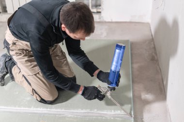 Çalışan bir poliüretan köpük Alçıpan doksan derece yapıştırma için kullanıyor. Genişleyen poliüretan köpük tutkal silah aplikatör tutan el