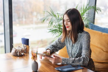 Genç kadın tablete yazarak, bir blog tutar, sohbet. Kafe modern coworking, serbest meslek eser bulunmaktadır. Başarılı insanlar, işadamı rahat kafede. Yüksek büyük pencereler