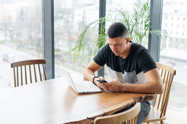 Successful people, businessman in comfortable cafe. Freelancer work on netbook in modern coworking. Young man drinking coffee from a Cup. Programmer at remote job. High large Windows