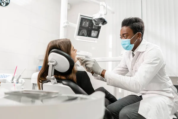 Doktor zachází se zuby. Mladý africký zubař s pacientem. Žena na zubařské židli na zubní klinice. Koncepce medicíny, zdraví, stomatologie. zubař ošetřující pacienta. — Stock fotografie