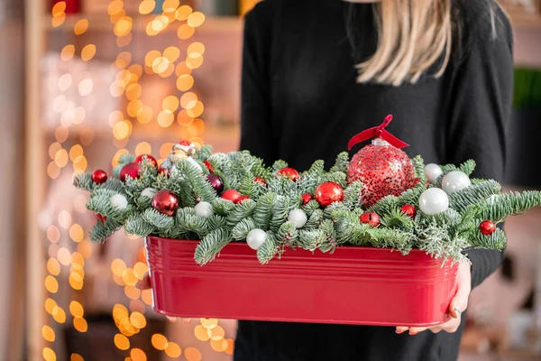 Bella disposizione natalizia di abete rosso fresco, palline rosse in una scatola di metallo rosso. L'umore natalizio. Bokeh di ghirlanda luci su sfondo . — Foto Stock