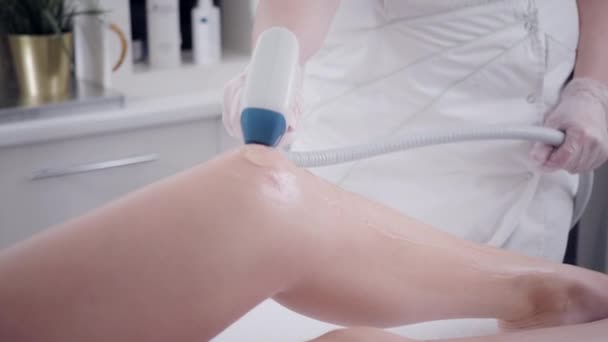 Primo piano Medico cosmetologo rende la procedura una giovane ragazza bruna. Epilazione laser e cosmetologia. Depilazione sulle gambe delle donne. presso la clinica cosmetica beauty spa . — Video Stock