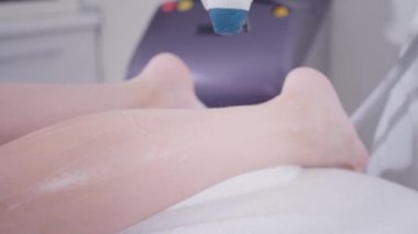 Yakın çekim Doktor kozmetolojist prosedürü genç bir kız esmer yapar. Lazer epilasyon ve kozmetoloji. Bayan ların bacaklarında epilasyon. kozmetik güzellik spa kliniğinde.