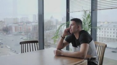 Genç adam telefonla konuşuyor. Modern çalışma ağları üzerinde serbest çalışan bir yazar. Uzaktan kumandalı programcı. Başarılı insanlar, rahat bir kafede iş adamı. Yüksek Büyük Pencereler