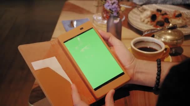 Joven escribiendo en una tableta, charlando, blogueando. Gente exitosa, hombre de negocios en una cafetería cómoda. Ventanas grandes altas — Vídeo de stock