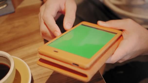 Joven escribiendo en una tableta, charlando, blogueando. Freelancer trabaja en netbook en coworking moderno. Programador en el trabajo remoto. Gente exitosa, hombre de negocios en una cafetería cómoda. Ventanas grandes altas — Vídeos de Stock