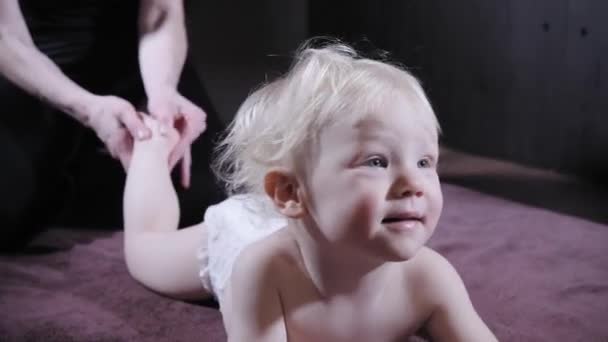 Babymassage. Mutter oder Therapeutin massiert ihr Baby zu Hause. Gesundheits- und Medizinkonzept. blonder Junge — Stockvideo