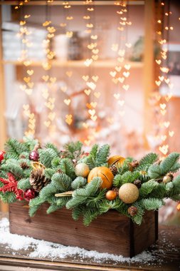 Noel havası. Rustik ahşap bir kutu içinde taze ladin güzel şenlikli düzenleme. Arka planda Garland ışıkları Bokeh kalpleri. Dilimler portakal, altın topları, koniler ile dekore