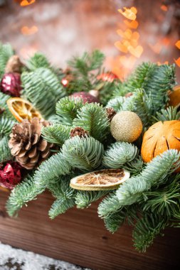 Noel havası. Rustik ahşap bir kutu içinde taze ladin güzel şenlikli düzenleme. Arka planda Garland ışıkları Bokeh kalpleri. Dilimler portakal, altın topları, koniler ile dekore