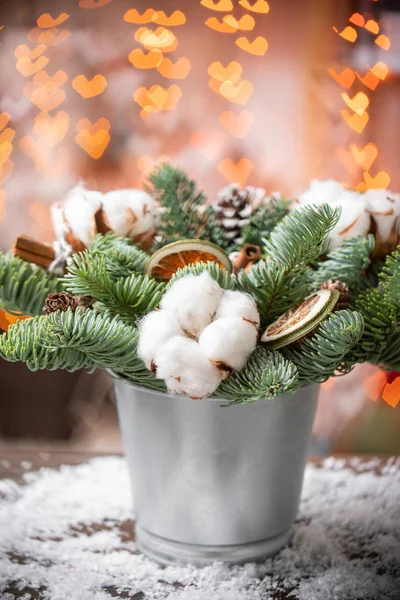 Weihnachtsstimmung. schönes festliches Arrangement aus frischen Fichten in einer rustikalen Holzkiste. Bokeh Herzen aus Girlanden Lichter auf dem Hintergrund. verziert mit Glöckchen, Kugeln Silber, weißer Baumwolle und Zimt — Stockfoto