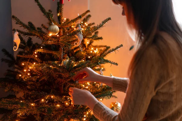 Szczęśliwa młoda kobieta dekorowanie choinki w domu. Ferie zimowe we wnętrzu domu. Złote i białe zabawki świąteczne, światła w garlandach. Naturalny duński świerk — Zdjęcie stockowe