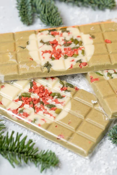 Handmade chocolates bar. Christmas theme. White chocolate bar with pistachio nuts and dried fruit cherries. . Copy space