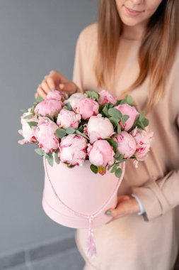 Pembe yuvarlak kutuda pembe şakayık. Katalog veya online mağaza için kadın elinde Güzel şakayık çiçek. Çiçek dükkanı konsepti. Çiçek teslimatı