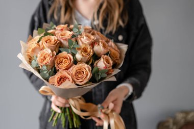 Çiçekler kahve rengi, okaliptüs ile kapuçino gül. Kadın elinde Küçük Güzel buketleri. Çiçek dükkanı konsepti. Çiçek teslimatı