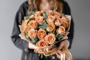 Çiçekler kahve rengi, okaliptüs ile kapuçino gül. Kadın elinde Küçük Güzel buketleri. Çiçek dükkanı konsepti. Çiçek teslimatı