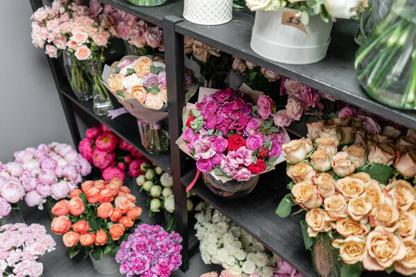 Вазы с разноцветными цветами, витрина цветочного магазина. Прекрасные весенние букеты. - Да. Маленький семейный бизнес. Рабочий флорист. копировальное пространство