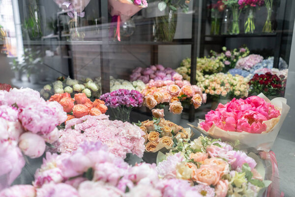 Вазы с разноцветными цветами, витрина цветочного магазина. Прекрасные весенние букеты. - Да. Маленький семейный бизнес. Рабочий флорист. копировальное пространство