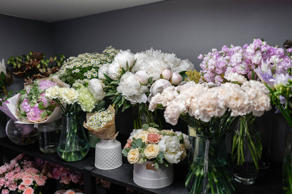 Вазы с разноцветными цветами, витрина цветочного магазина. Прекрасные весенние букеты. - Да. Маленький семейный бизнес. Рабочий флорист. копировальное пространство