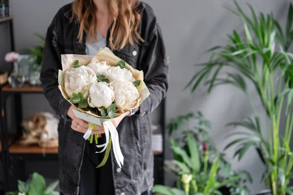 Floral shop and flowers delivery concept. White peonies in womans hands. Beautiful fresh peony flower for catalog or online store.