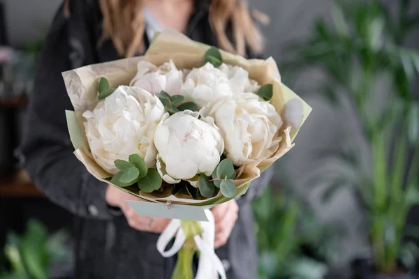 Floral shop and flowers delivery concept. White peonies in womans hands. Beautiful fresh peony flower for catalog or online store.