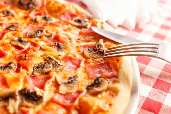 Pizza with ham and mushrooms. Delicious hot food sliced and served on white platter. Menu photo, Italian fast food.