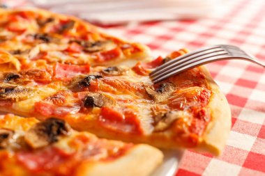 Yakın çatal bir parça alır. Jambonlu ve mantarlı pizza. Lezzetli sıcak gıda dilimlenmiş ve beyaz tabakta servis edilir. Menü fotoğrafı, İtalyan fast food.