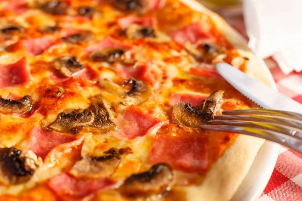 Pizza with ham and mushrooms. Delicious hot food sliced and served on white platter. Menu photo, Italian fast food.
