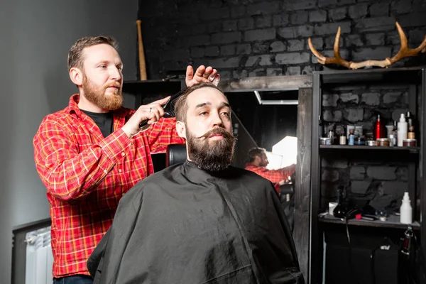 Barber is making the beard shape. Beard cutting, face care. Work in barber shop.