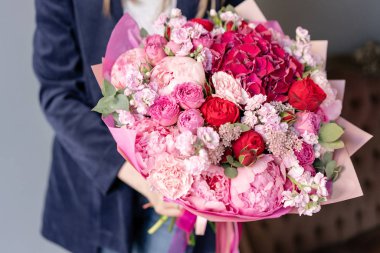 Pembe şakayıkve kırmızı ortanca. Kadın elinde karışık çiçek güzel buket. Çiçek dükkanı konsepti . Yakışıklı taze buket. Çiçek teslimatı. Kırmızı ve pembe renk.