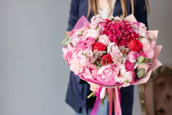 Pedónias cor-de-rosa e hortênsias vermelhas. Belo buquê de flores mistas na mão da mulher. Conceito de loja floral. Bonito buquê fresco. Entrega de flores. Cor vermelha e rosa . — Fotografia de Stock