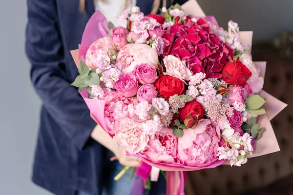 Pembe şakayıkve kırmızı ortanca. Kadın elinde karışık çiçek güzel buket. Çiçek dükkanı konsepti . Yakışıklı taze buket. Çiçek teslimatı. Kırmızı ve pembe renk.