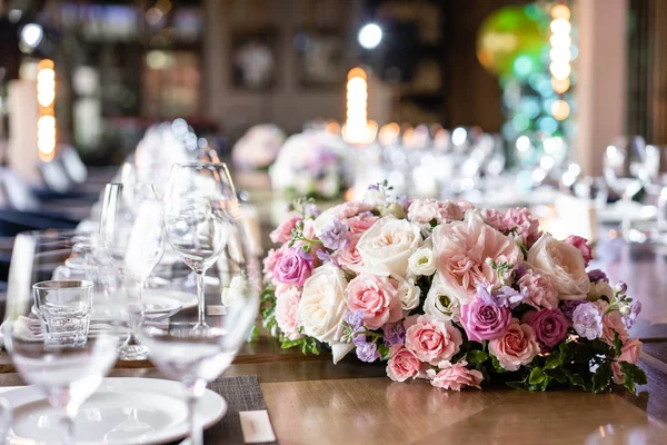 Şarap bardakları ön planda. Düğün Ziyafeti ya da gala yemeği. Misafirler için sandalye ve masa, çatal bıçak takımı ve tabak ile servis.