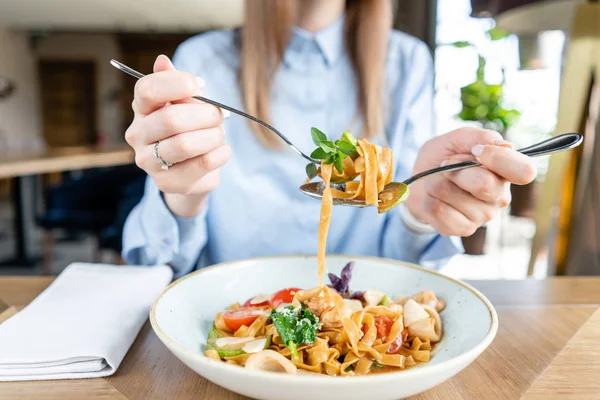 La mujer come pasta italiana con mariscos y salsa de tomate. Pasta Gamberini. Close-up tagliatelle enrollarlo alrededor de un tenedor con una cuchara. Queso parmesano — Foto de Stock