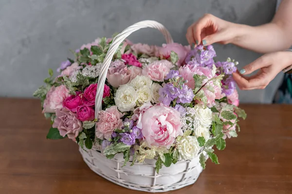 Flower arrangement in Wicker basket. Beautiful bouquet of mixed flowers in woman hand. Floral shop concept . Handsome fresh bouquet. Flowers delivery