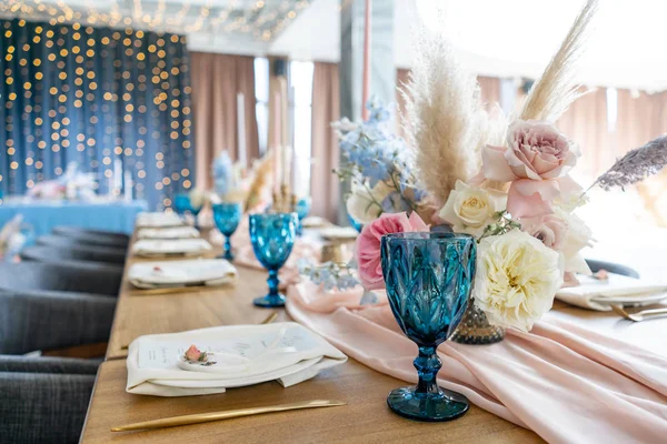 Luxe diner feestzaal in het restaurant. Mooie en verfijnde decoratie van het huwelijksfeest. Feestzaal geserveerd tafel met een beige roze tafelkleed, borden en kandelaars met kaarsen. — Stockfoto