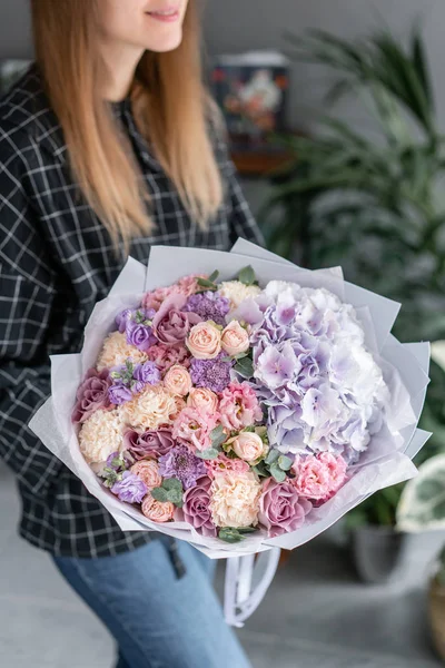 Hermoso ramo de flores mixtas en mano de mujer. Concepto de tienda floral. Bonito ramo fresco. Entrega de flores. Color rojo y rosa . — Foto de Stock