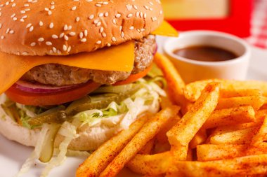 Restoranda lezzetli Cheeseburger. Susamlı çörek, etli börek, domates, marul ve turşu. Patates kızartması ile servis edilir