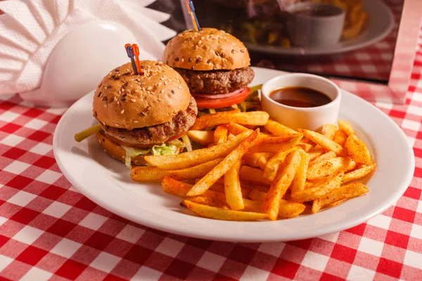 Dos mini hamburguesas en el restaurante. Pan de sésamo, carne Patty, tomate, lechuga y pepinillo. Sabroso Servido con papas fritas — Foto de Stock