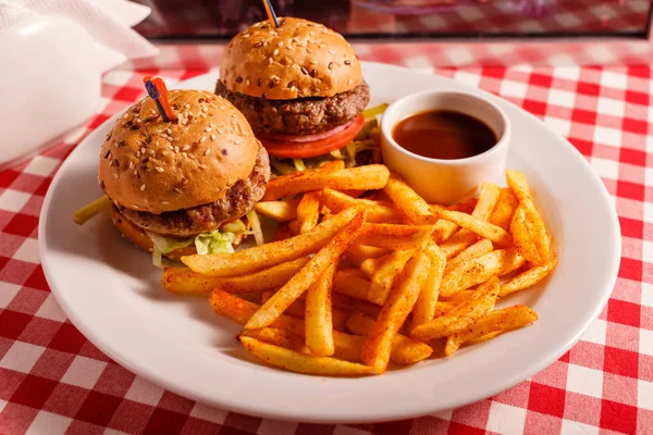 Dos mini hamburguesas en el restaurante. Pan de sésamo, carne Patty, tomate, lechuga y pepinillo. Sabroso Servido con papas fritas — Foto de Stock