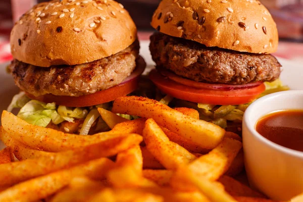 Dos mini hamburguesas en el restaurante. Pan de sésamo, carne Patty, tomate, lechuga y pepinillo. Sabroso Servido con papas fritas — Foto de Stock