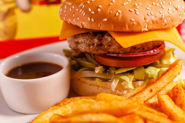 Cierra Tasty Cheeseburger en el restaurante. Pan de sésamo, carne Patty, tomate, lechuga y pepinillo. Servido con papas fritas — Foto de Stock