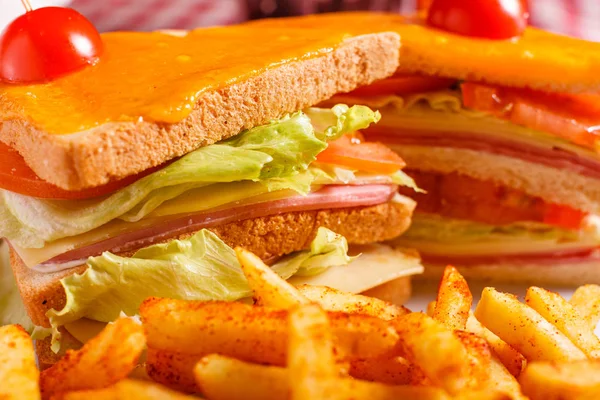 Tasty grilled sandwich in the restaurant. Club sandwich with ham, tomato, cheese and lettuce. Served with French fries