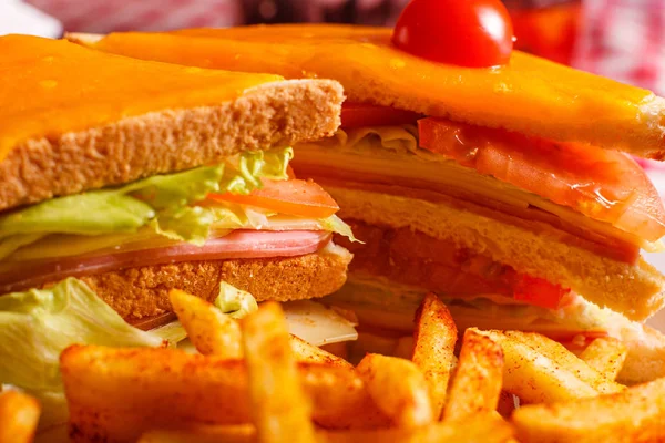 Sabroso sándwich a la parrilla en el restaurante. Sándwich de club con jamón, tomate, queso y lechuga. Servido con papas fritas — Foto de Stock