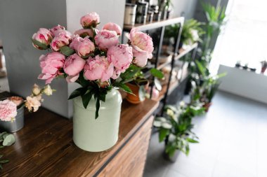 Çiçekçi dükkanının tezgahı. Metal vazoda pembe şakayıklar. Katalog veya online mağaza için güzel şakayık çiçek. Çiçek dükkanı konsepti . Güzel taze kesme buketi. Çiçek teslimatı