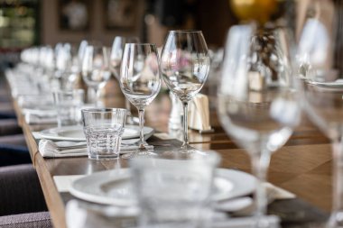 Şarap bardakları ön planda. Düğün Ziyafeti ya da gala yemeği. Misafirler için sandalye ve masa, çatal bıçak takımı ve tabak ile servis.